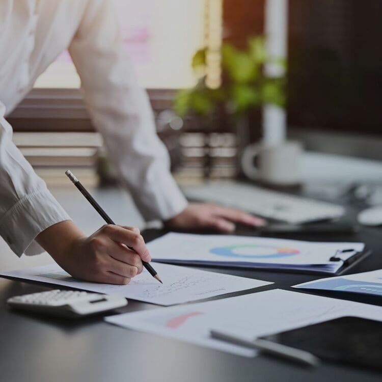 Person bei der Planung von IT-Projekten mit Diagrammen und Notizen auf einem Schreibtisch