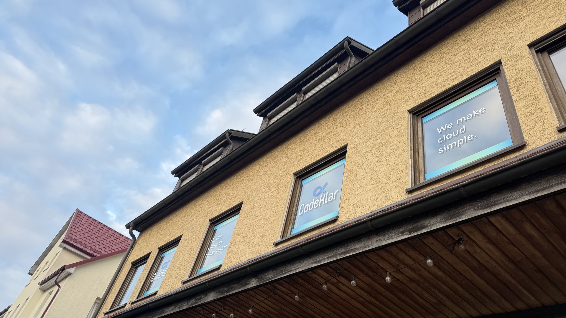 Das CodeKlar-Gebäude zeigt Fenster mit dem Slogan "We make cloud simple" und spiegelt das Thema IT-Sicherheit wider.